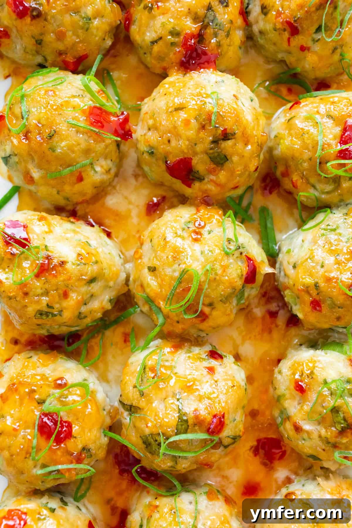 Effortless Thai Baked Chicken Meatballs 7 Easy Thai Baked Chicken Meatballs topped with sweet chili sauce and green onions in a baking dish.