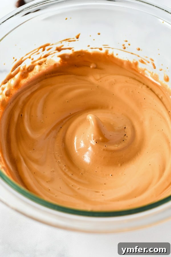 Close-up shot of the whipped pumpkin spice coffee mixture in a glass bowl, showcasing its creamy, light brown texture.
