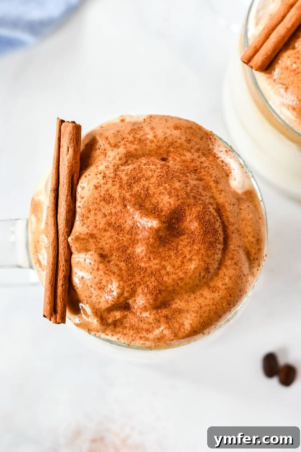 A glass of pumpkin spice whipped coffee, garnished with a fine dusting of pumpkin pie spice on top of the foam.