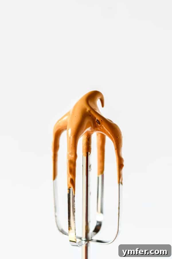 The pumpkin spice whipped coffee mixture being prepared in a mixing bowl with a KitchenAid hand mixer, showing the light, creamy texture.