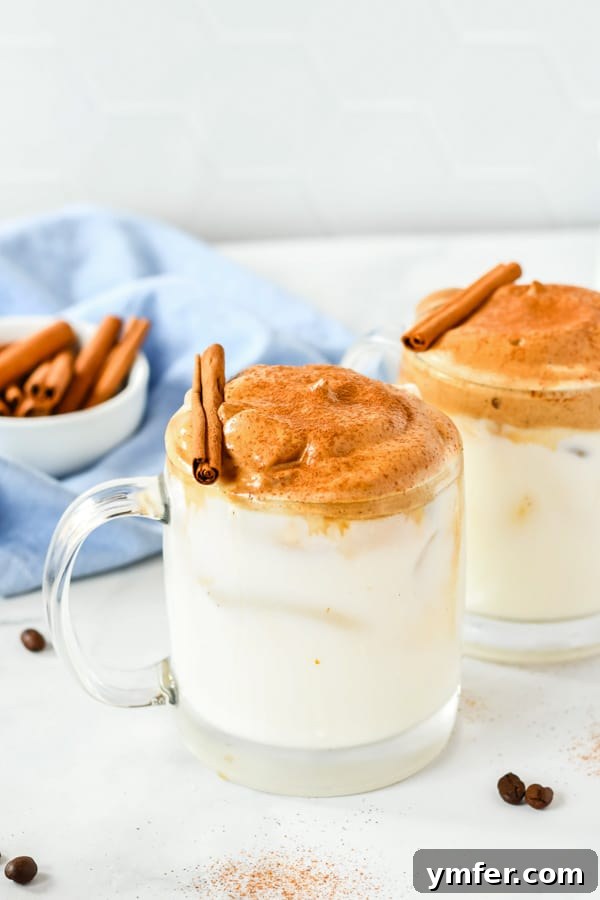 Two aesthetically pleasing mugs of pumpkin spice whipped coffee, one served hot and one iced, demonstrating the versatility of the drink.