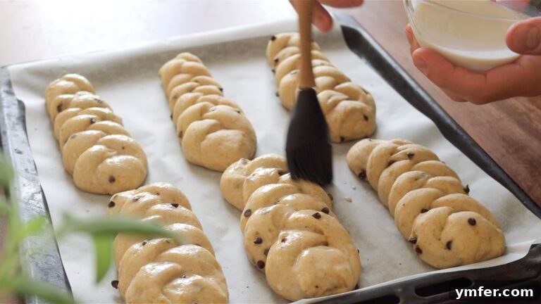 Brushing vegan chocolate chip brioches with plant milk before baking