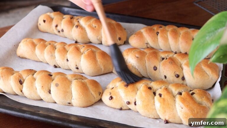 Freshly baked vegan brioches being brushed with water to keep them soft