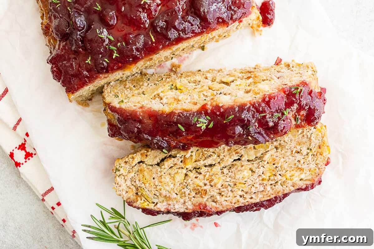Festive Turkey Meatloaf 6 Sliced Thanksgiving turkey meatloaf surrounded by fresh herbs, creating a beautiful presentation.