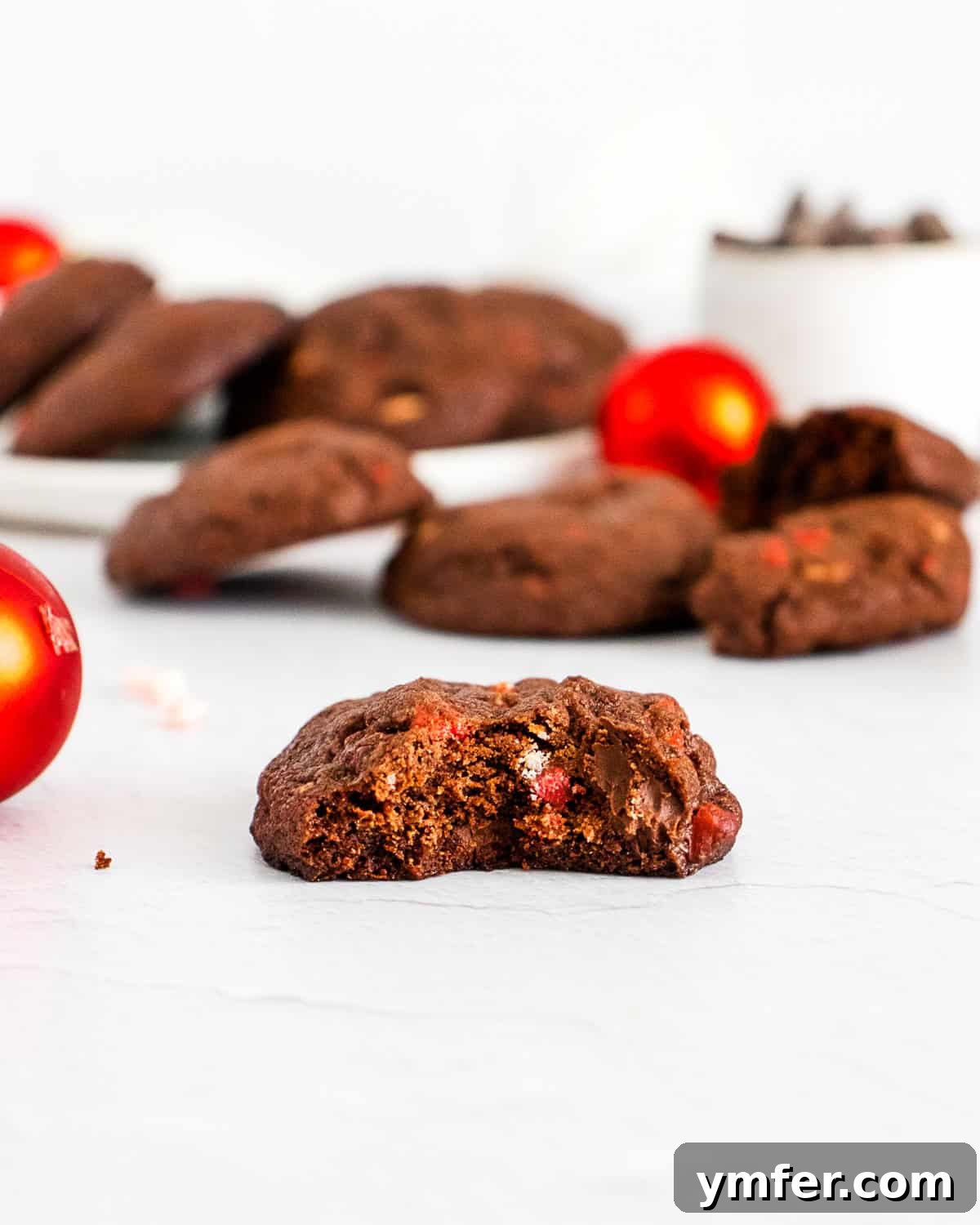 Peppermint Chocolate Bark Bites 4 A close-up shot of a chocolate peppermint bark cookie with a bite taken out, revealing its fudgy interior and speckled peppermint pieces.
