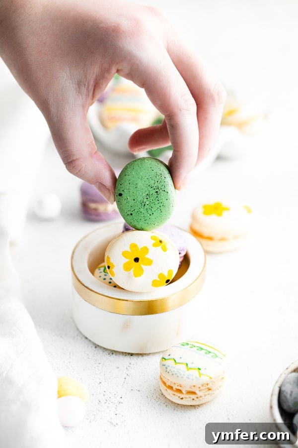 Pastel Easter Macarons 6 A hand holding a vibrant green Easter egg macaron, highlighting its delicate feet and smooth shell.