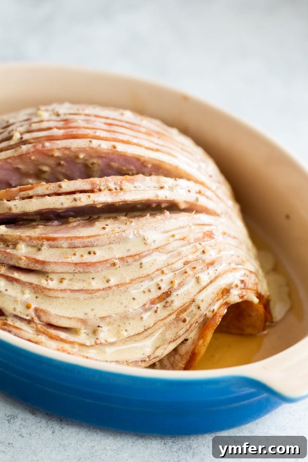 Honey Mustard Glazed Spiral Ham 5 An unbaked spiral ham generously covered in the honey mustard glaze, resting in a baking dish before entering the oven.