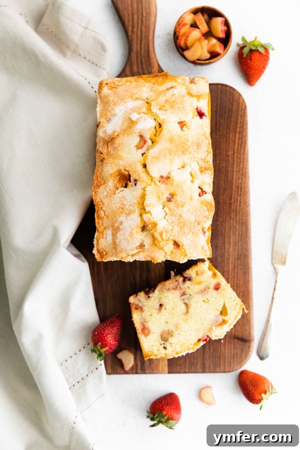 Sweet & Tangy Strawberry Rhubarb Pound Cake 3 Close-up of strawberry rhubarb pound cake slices arranged on a wooden serving board, showcasing the inviting sugary topping.