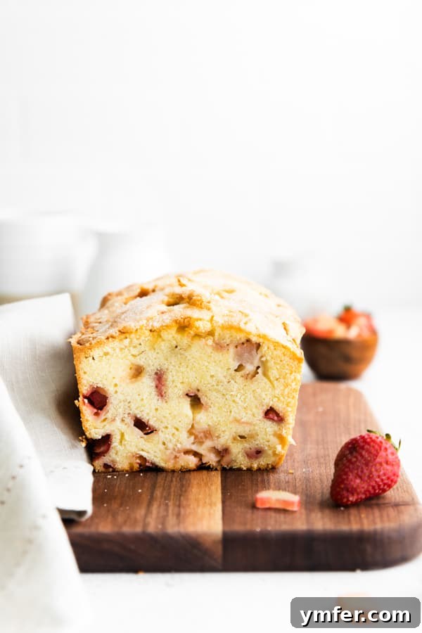 Sweet & Tangy Strawberry Rhubarb Pound Cake 4 A close-up view of a slice of strawberry rhubarb pound cake, highlighting the generous chunks of fresh rhubarb and strawberries within the moist cake.