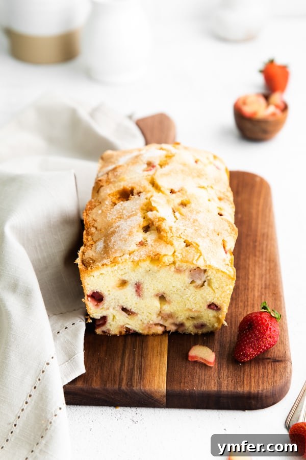 Sweet & Tangy Strawberry Rhubarb Pound Cake 6 A complete strawberry rhubarb pound cake on a wooden serving board, garnished with fresh strawberries, ready to be enjoyed.
