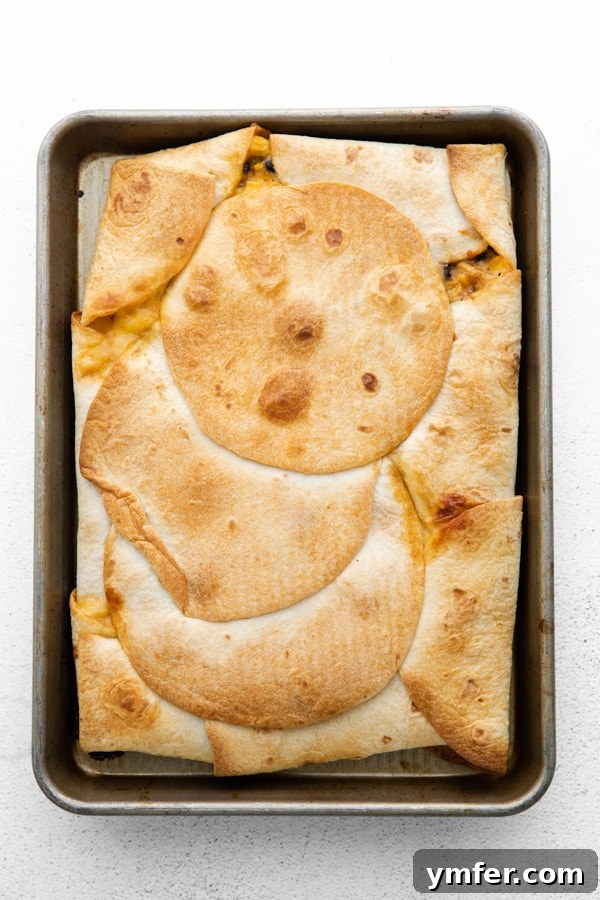 One-Pan Chicken Quesadillas 5 A fully cooked sheet pan chicken quesadilla, sliced into neat squares on a baking sheet.