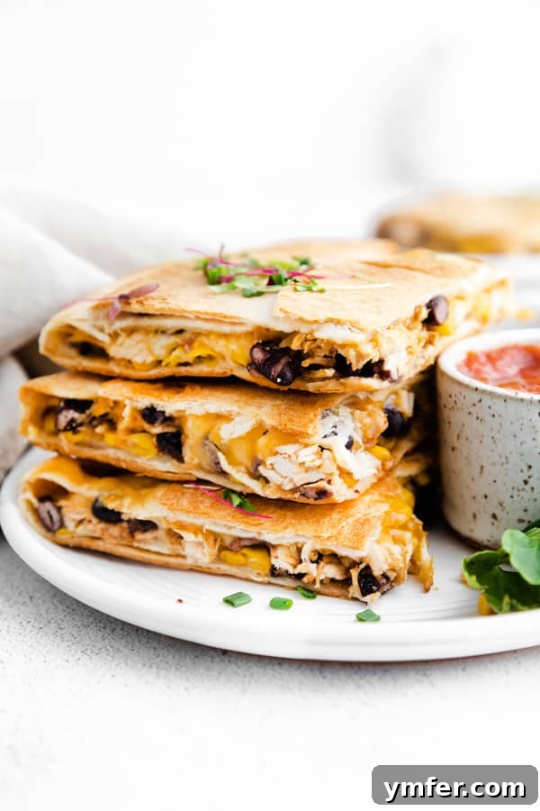 One-Pan Chicken Quesadillas 6 Stacked pieces of sheet pan chicken quesadillas on a rustic ceramic plate, garnished with fresh herbs.