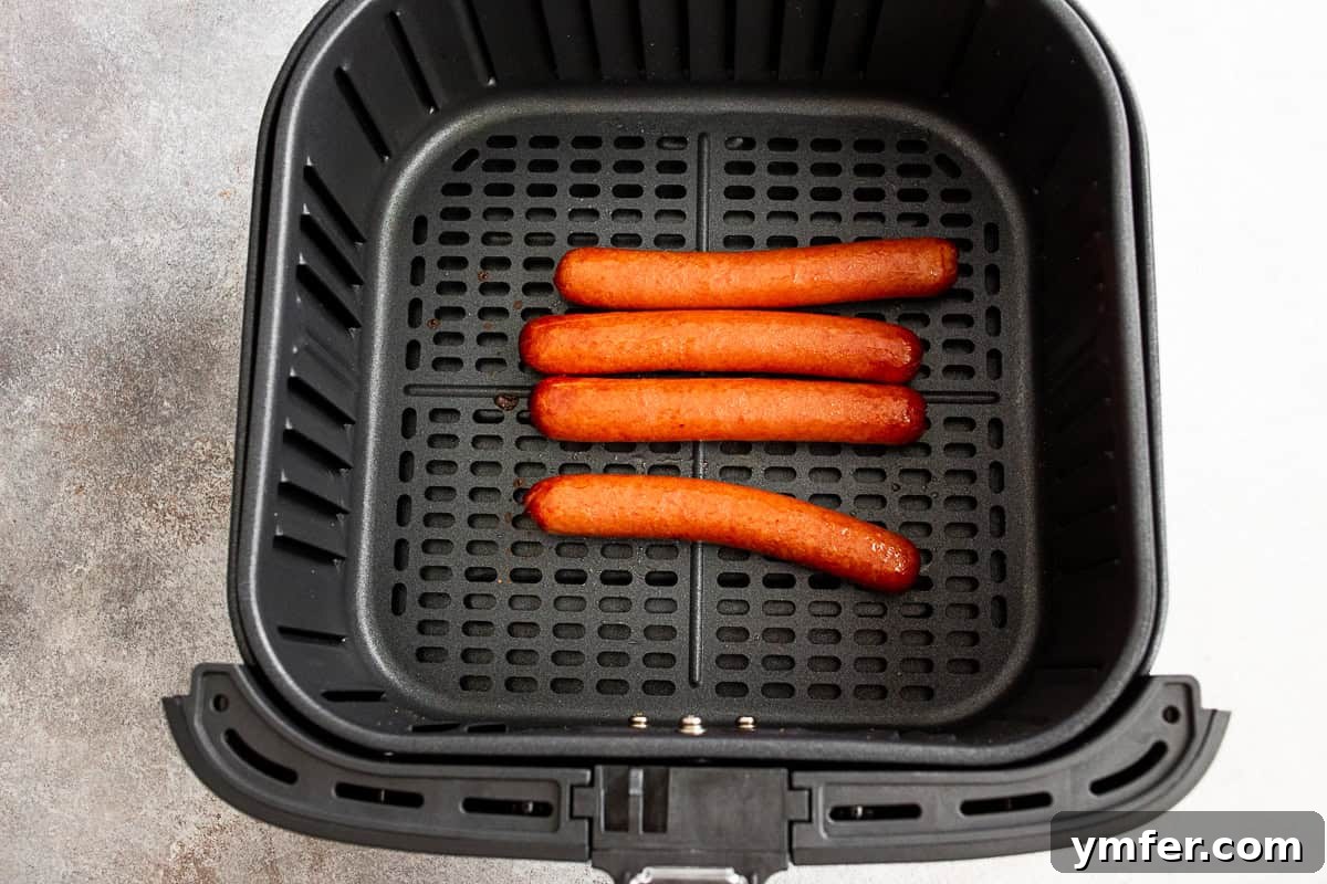 Cooked hot dogs in an air fryer basket.