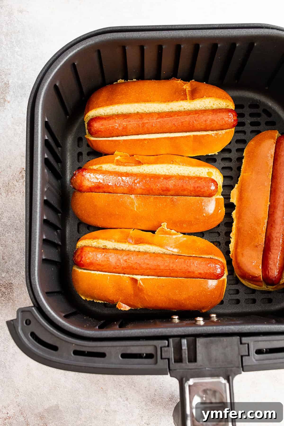 Cooked air fryer hot dogs in an air fryer basket.
