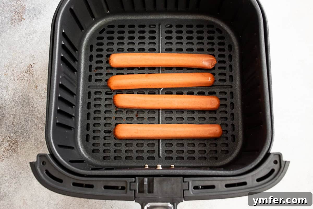 Uncooked hot dogs in an air fryer basket.