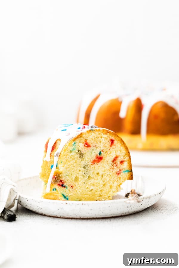 Red, White, and Bundt 3 A perfectly sliced Fourth of July Bundt Cake revealing its colorful sprinkle-filled interior, ready to be served.