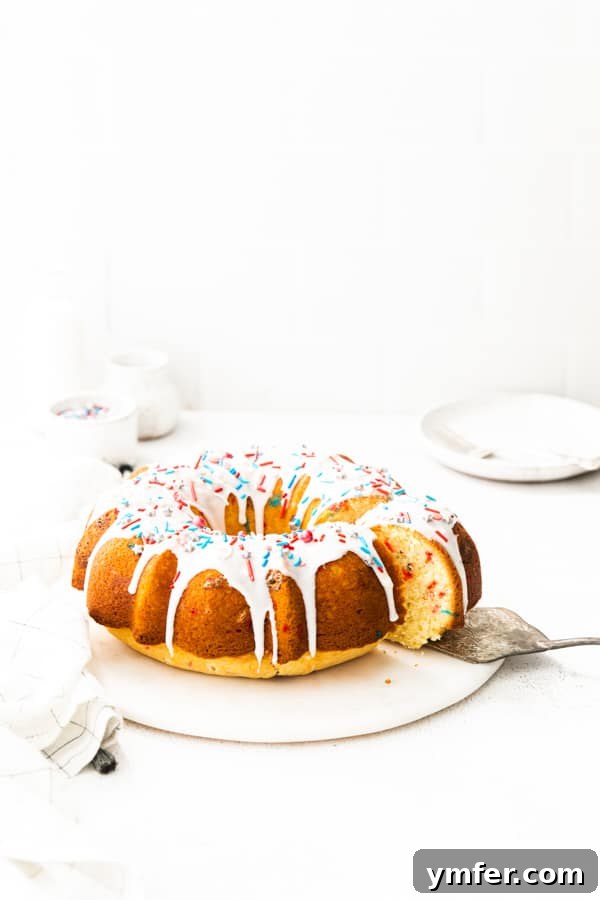 Red, White, and Bundt 4 A hand gently cutting a slice from a patriotic Fourth of July Bundt Cake, revealing a vibrant sprinkle-filled interior.
