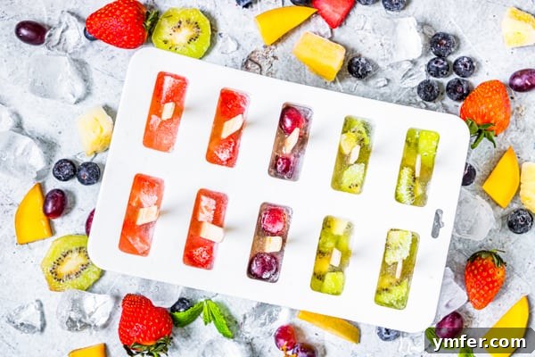 A close-up view of vibrant rainbow fruit popsicles nestled in a clear popsicle mold, showcasing the distinct layers of colorful fruit before freezing.