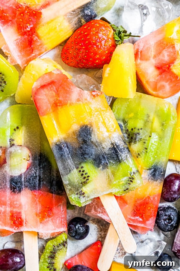 A tantalizing close-up of a rainbow fruit popsicle with a bite taken out, revealing the colorful layers and the juicy freshness of the fruit inside.
