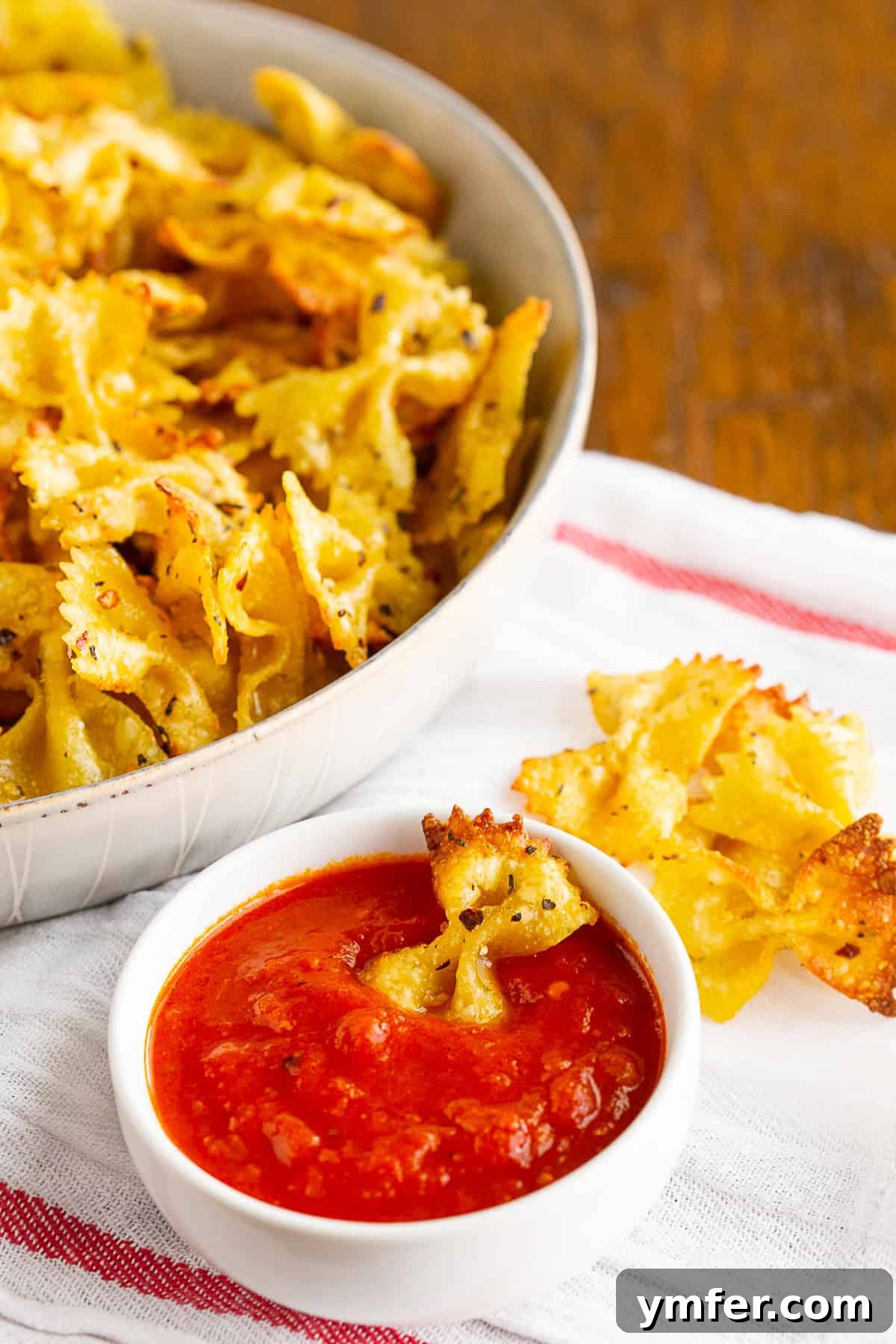 Crispy Air Fryer Pasta Chips 6 Air fryer pasta chips beautifully arranged in a bowl with a small ramekin of tomato sauce for dipping.