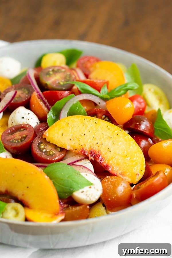 Sun-Kissed Peach Tomato Caprese 3 Tomato Peach Caprese Salad in a bowl with fresh basil.