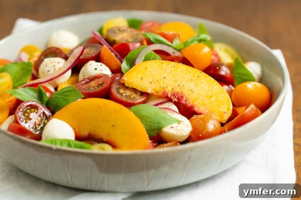 Sun-Kissed Peach Tomato Caprese 5 Tomato Peach Caprese Salad served in a grey bowl.