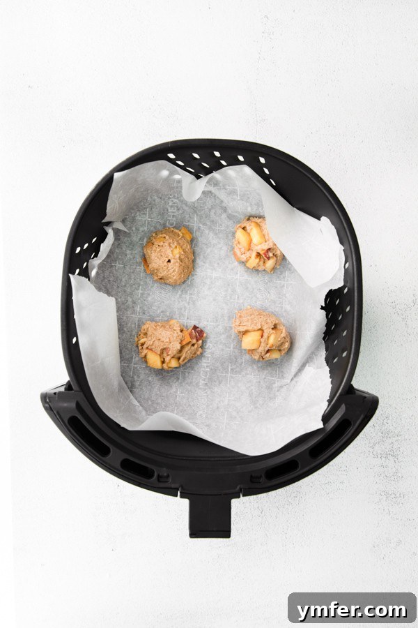 Air-Fried Peachy Delights 4 Uncooked air fryer peach fritters arranged in an air fryer basket, ready for cooking.