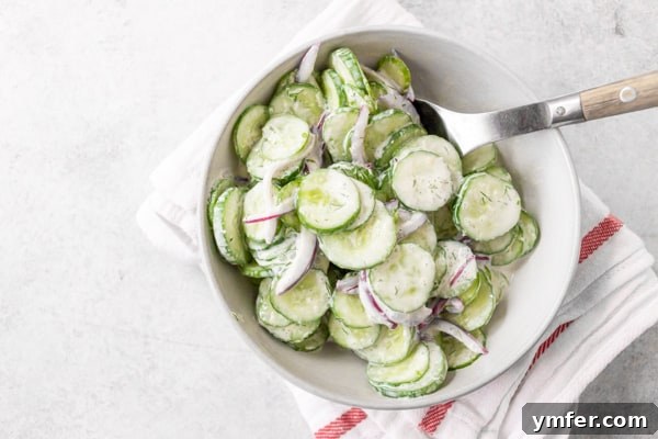Cool Cucumber Salad with Creamy Horseradish 3 creamy horseradish cucumber salad in a ceramic bowl with a wooden spoon.