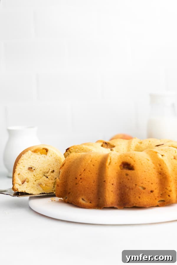 Sun-Kissed Peach Bundt 4 A delectable slice of peach bundt cake being carefully removed from the main cake, ready to be served.