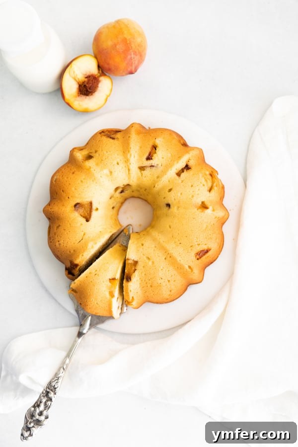 Sun-Kissed Peach Bundt 5 A slice of peach bundt cake resting on a serving knife, ready to be enjoyed from a beautifully arranged platter.