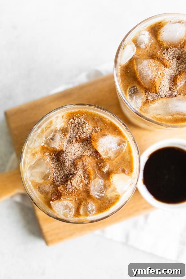 Spiced Apple Crisp Macchiato 5 A vibrant Apple Crisp Macchiato in a clear glass, topped with a dusting of cinnamon sugar and a luxurious caramel drizzle.