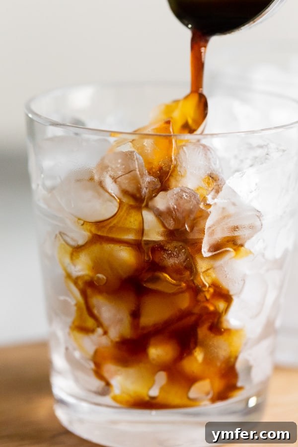 Spiced Apple Crisp Macchiato 6 Homemade apple brown sugar molasses coffee syrup being poured into a glass filled with ice, ready for the other macchiato ingredients.