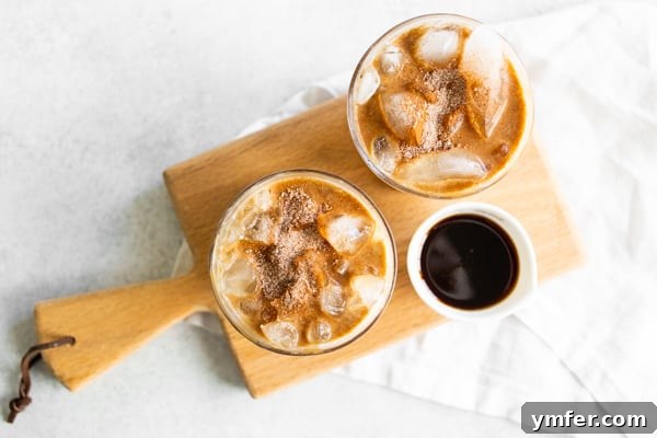 Spiced Apple Crisp Macchiato 8 Two enticing Apple Crisp Macchiato drinks, served on a miniature wooden cutting board, ready for enjoyment.