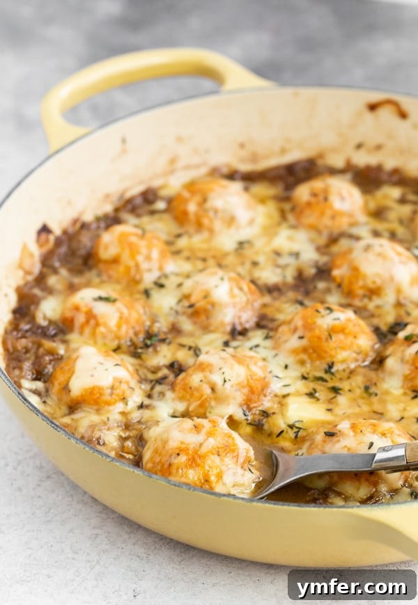 French Onion Chicken Meatballs simmering in a pan, being scooped out for serving, highlighting the golden brown meatballs and rich sauce.