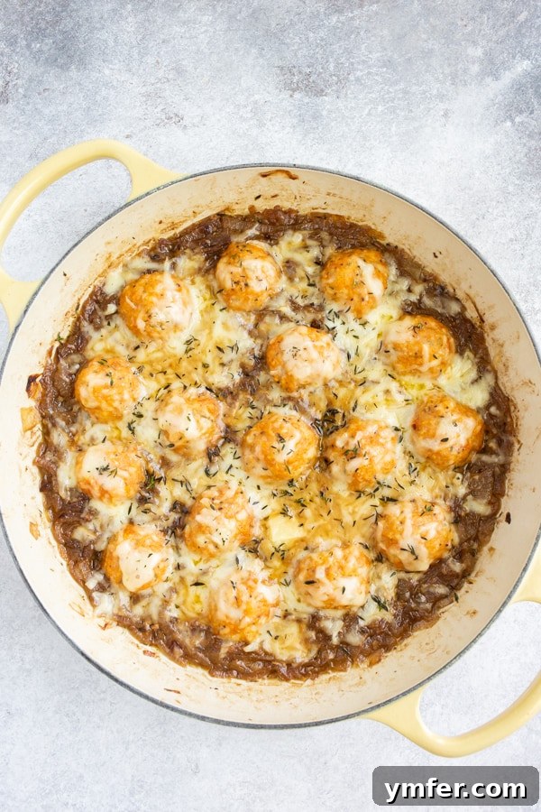 French Onion Chicken Meatballs in a skillet, generously topped with melted cheese, glistening under the heat.