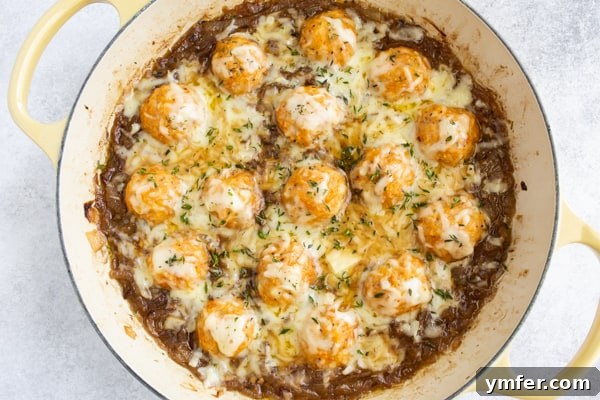 French Onion Chicken Meatballs presented in a round baking dish, generously covered with melted Gruyere cheese, ready to be served.