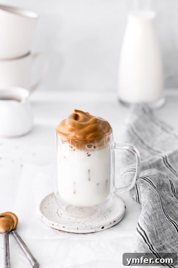 Maple Velvet Coffee 2 A glass cup filled with Maple Whipped Coffee, showcasing the rich, foamy topping over iced milk, ready to be enjoyed.