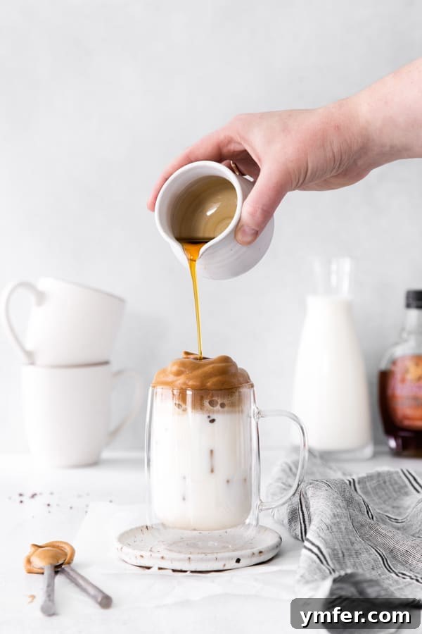 Maple Velvet Coffee 5 A close-up of a hand drizzling extra maple syrup over the creamy Maple Whipped Coffee, enhancing its visual appeal and flavor.