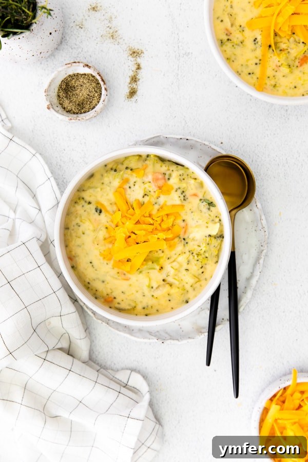Velvety Instant Pot Broccoli Cheddar Delight 2 A steaming bowl of homemade Instant Pot Broccoli Cheddar Soup, garnished with fresh cheddar cheese shreds and a sprig of parsley, with a spoon ready to dive in.