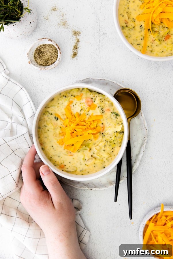 Velvety Instant Pot Broccoli Cheddar Delight 6 A bowl of Instant Pot Broccoli Cheddar Soup, with a hand gently touching the side of the bowl, suggesting warmth and comfort.