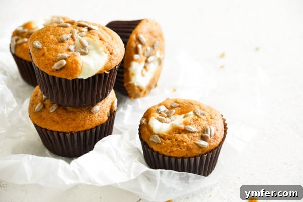 Heavenly Pumpkin Cream Cheese Swirls 7 Pumpkin Cream Cheese Muffins stacked on a white board.