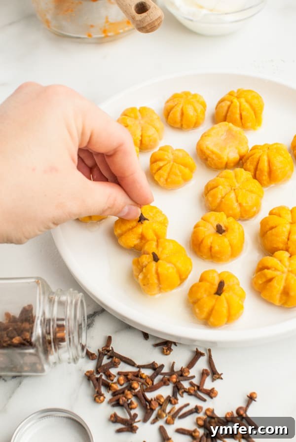 Autumn Pumpkin Gnocchi Pillows 7 Cooked pumpkin shaped gnocchi with whole cloves being inserted as stems.