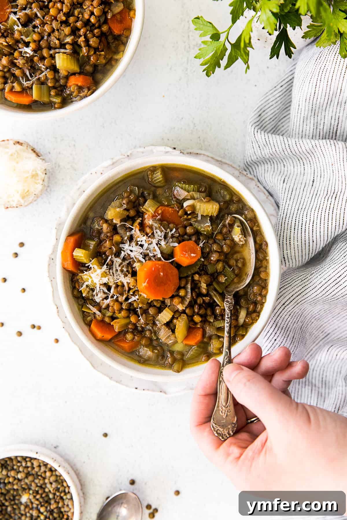 Nourishing French Lentil Potage 7 Healthy French Lentil Soup in a bowl with a hand going in for a spoonful.