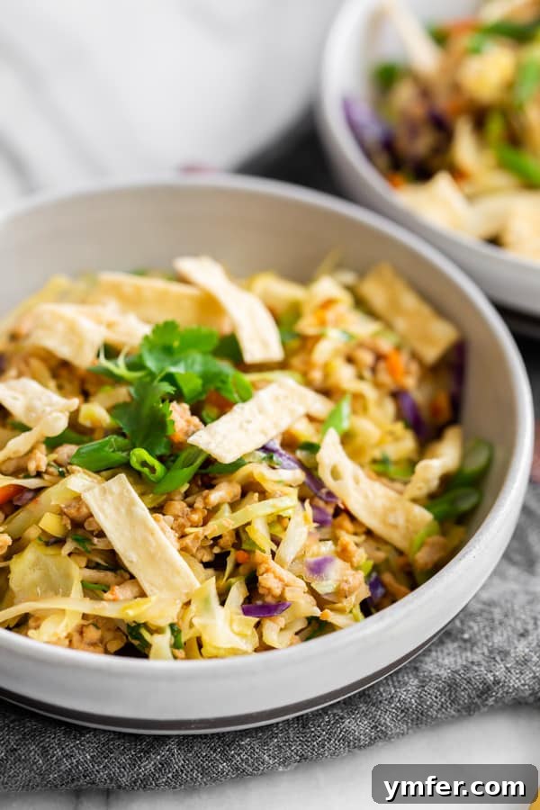 A large ceramic bowl filled with a generous serving of Ground Chicken Egg Roll Bowl, showcasing the vibrant ingredients and inviting textures.