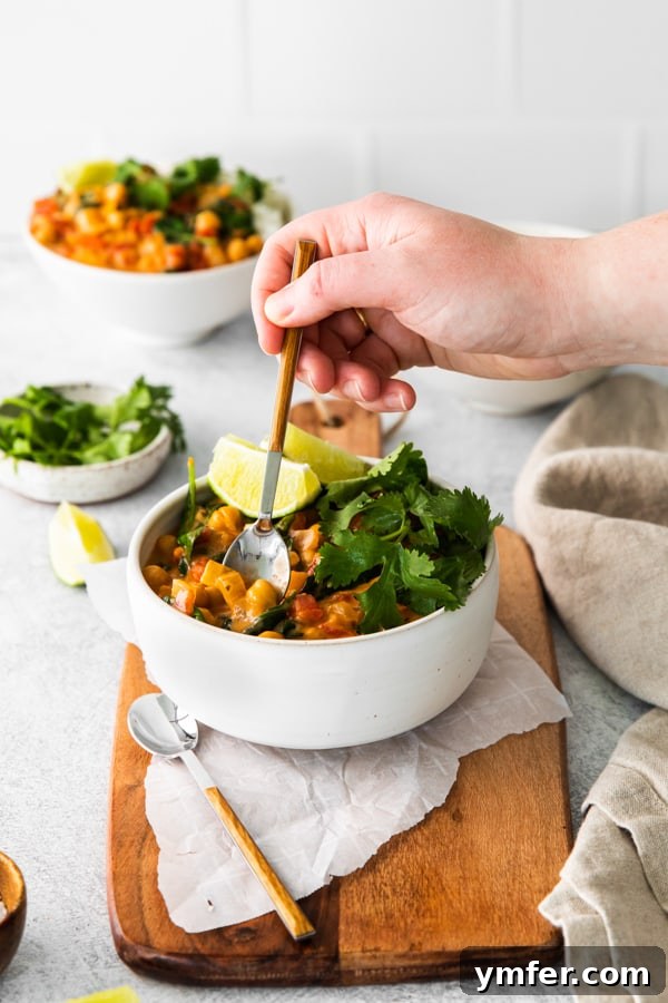 Hearty Vegan Chickpea Curry 4 A hand reaching into a bowl of Vegan Chickpea Curry, ready for a bite.