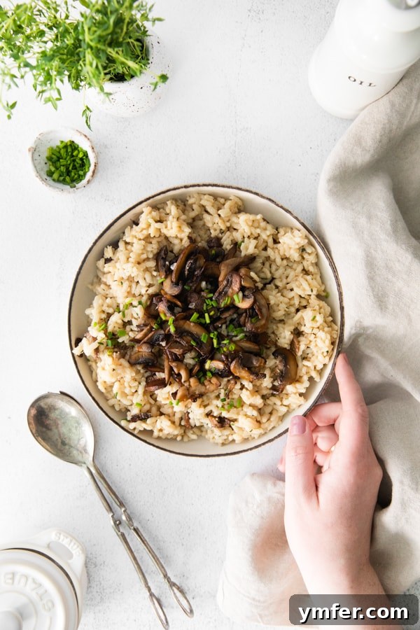 Earthy Wild Mushroom Risotto 4 A hand reaching into a bowl of freshly made wild mushroom risotto, highlighting its rich texture.