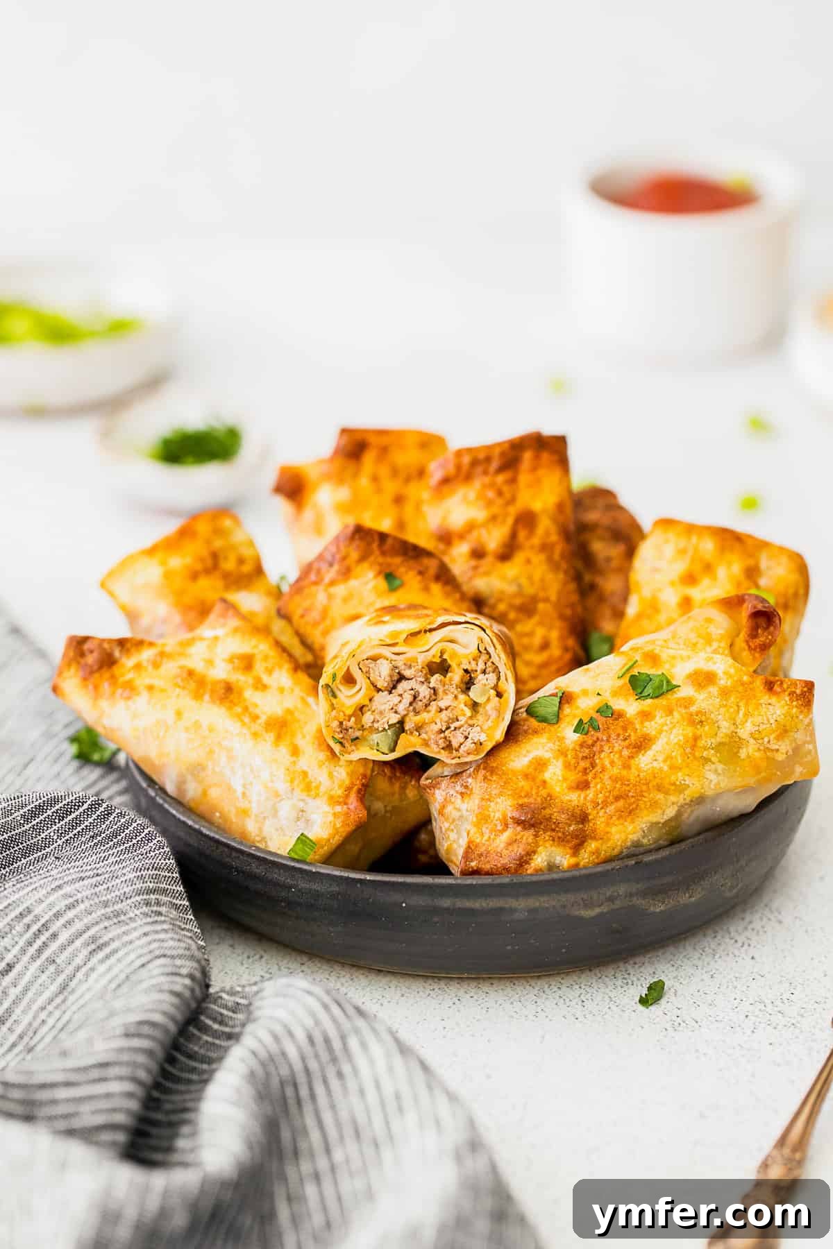 Crispy Air Fryer Cheeseburger Rolls 2 Air Fryer Cheeseburger Egg Rolls cut in half to show filling.