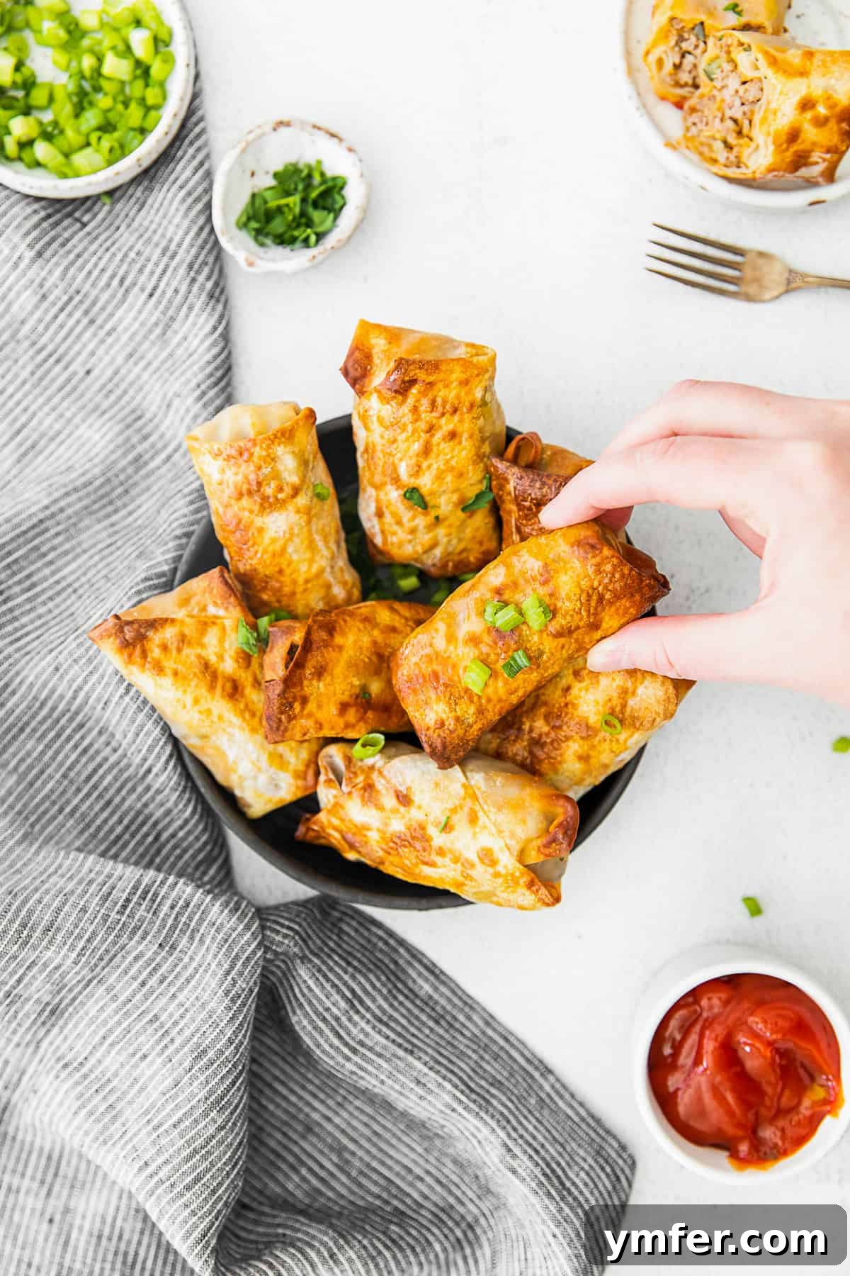 Crispy Air Fryer Cheeseburger Rolls 10 A hand grabbing a cheeseburger egg roll.