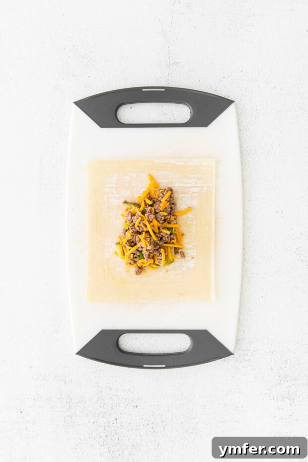 Crispy Air Fryer Cheeseburger Rolls 5 cheeseburger egg roll filling on a egg roll wrapper.