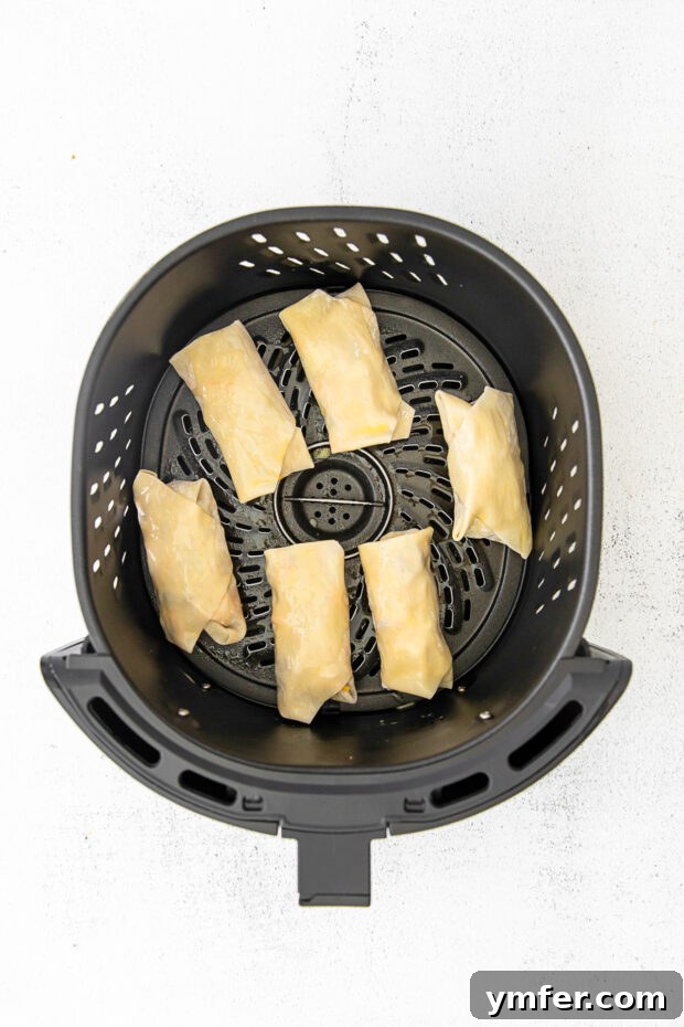 Crispy Air Fryer Cheeseburger Rolls 6 cheeseburger egg rolls in an air fryer basket.